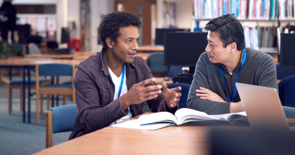 Two teachers in conversation in a library