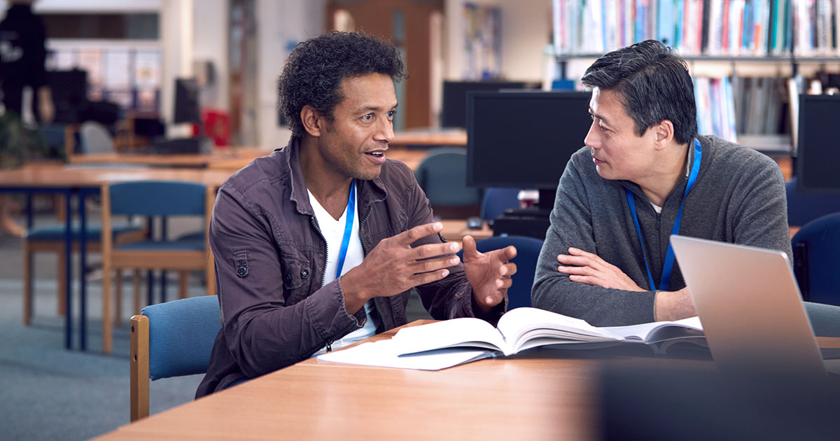 Two teachers in conversation in a library