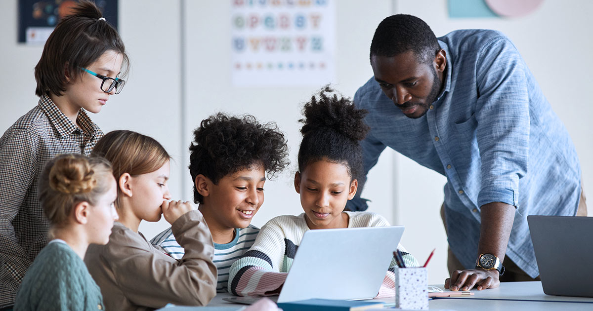 Teacher helping students on a computer in classroom