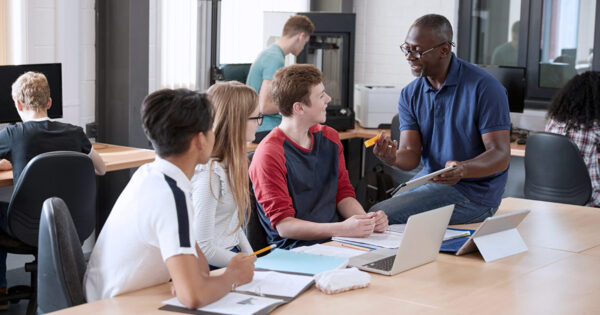 Students in an open concept classroom listening to a teacher