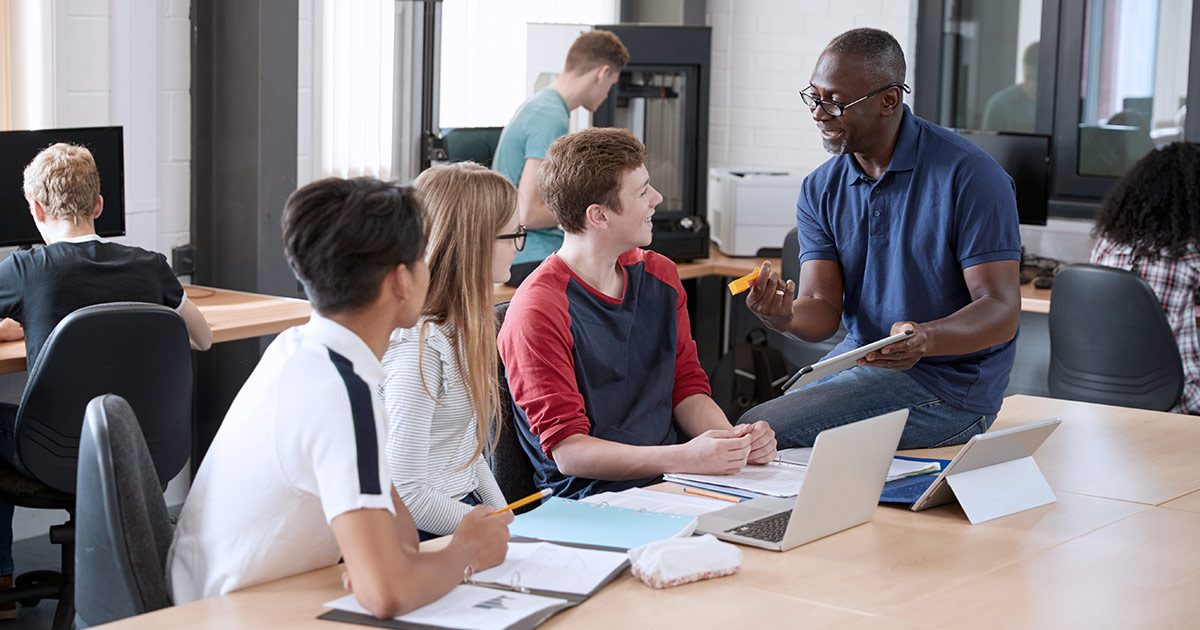 Students in an open concept classroom listening to a teacher